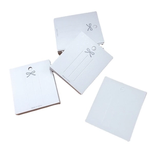 White cardboard hair clip cards with silver bow print and pre-cut holes for packaging