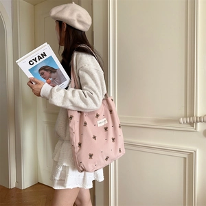 Pink corduroy tote bag with bear embroidery shown worn over the shoulder by a model
