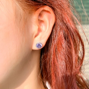 Close-up of a sparkling 8mm purple crown-shaped stud earring worn on a model's ear