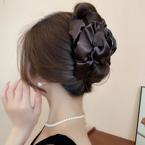 Detail of a large dark brown satin pleated hair claw clip shown in an elegant hairstyle