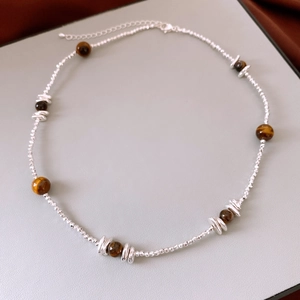 Vue détaillée des perles oeil de tigre et anneaux en argent sur un collier vintage ajustable