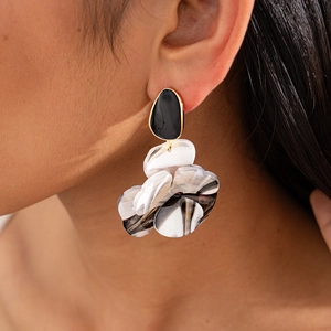 Boucles d'oreilles fleurs en résine marbrée avec bords dorés portées par un mannequin