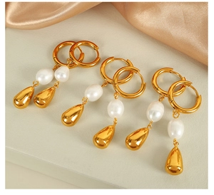 Dettaglio di tre paia di eleganti orecchini con perle dorate su sfondo di seta