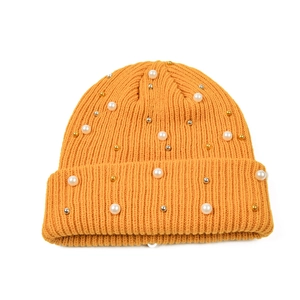Dettaglio della trama a maglia e perle cucite su un berretto invernale giallo senape