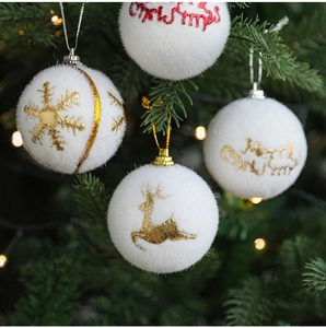 Close-up of white flocked Christmas ball ornaments with golden elk and Merry Christmas text