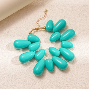Detail of turquoise acrylic teardrop bead necklace with gold clasp and extension chain