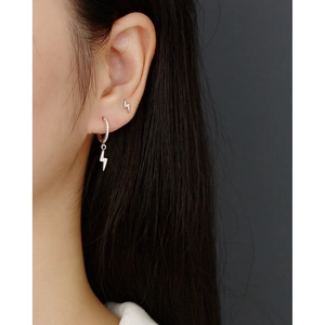 Close-up of sparkling S925 sterling silver lightning bolt earrings on model's ear