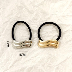 Detail view of wavy gold and silver metal hair ties measuring 1.5cm by 4cm on white paper