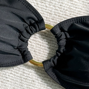 Vue détaillée du tissu bikini noir avec un anneau décoratif en métal doré sur le pli