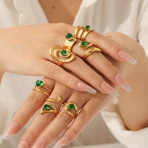 Close-up of gold-plated rings with green zircon stones worn by a model in soft light