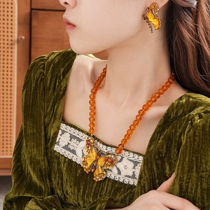 Close-up of vintage amber beaded necklace and butterfly pendant set on model