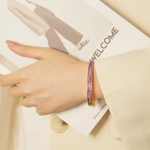 Golden titanium steel bracelet with purple square zircon worn by a fashion model