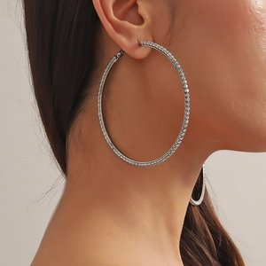 Close-up of large silver hoop earrings with shimmering white rhinestones worn by a model