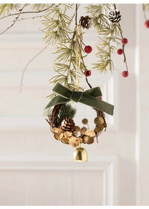 Detailaufnahme eines handgefertigten Weihnachtskranzes mit Samtschleife und Goldglocke