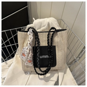 Détail d'un sac cabas en paille tressée avec poche en cuir noir et foulard décoratif
