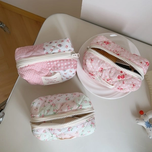 Three-piece set of floral quilted makeup bags in pink and green patterns on table