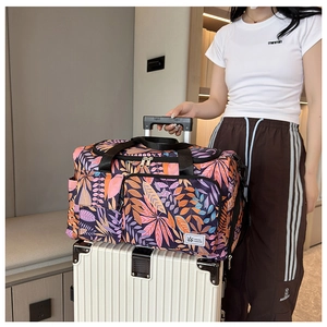 Detail of floral purple travel tote bag with trolley sleeve secured on a suitcase