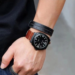Men's leather bracelet with quote and watch featuring a brown strap on a wrist