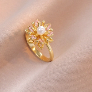 Detailaufnahme eines goldenen Blumenrings mit weißer Perle und rosa Edelsteinen auf Seide