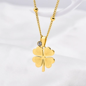 Detailed view of a gold clover necklace with emerald zircon and delicate sunburst texture