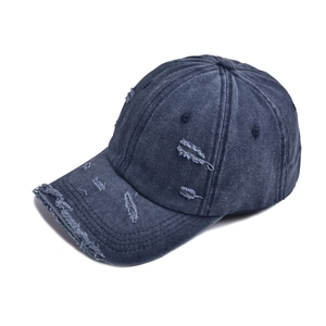 Detailed close-up of distressed denim baseball cap with vintage frayed edges and texture