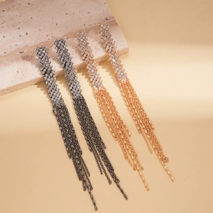 Detailed view of luxury gold and dark grey tassel earrings with sparkling rhinestones on stone