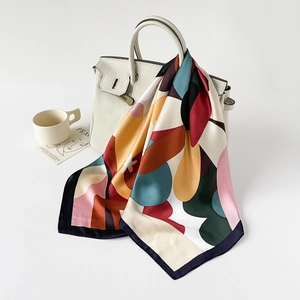 Silk-feel floral square scarf tied on a white leather handbag for a French luxury style
