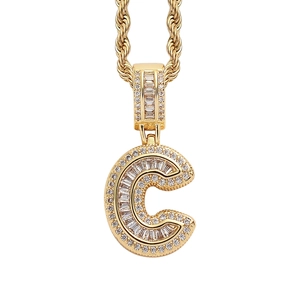 Macro shot of gold letter C pendant with square zircons and twisted rope chain