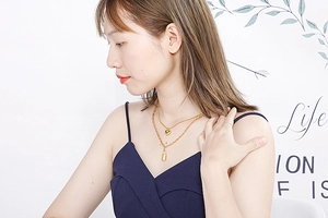 Gold double-layered stainless steel necklace featuring heart and lock pendants on a model