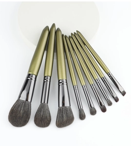 Detail of 9-piece olive green makeup brush set with soft grey bristles on white background
