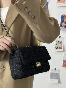 Detail of classic black tweed chain bag featuring a gold square twist lock on a flap closure