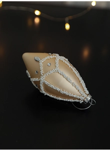 Macro shot of champagne gold teardrop Christmas ornament with white beaded mesh texture