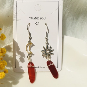 Detailed macro shot of asymmetrical sun and moon wire-wrapped quartz earrings