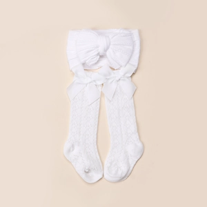Gros plan du bandeau tricoté blanc et chaussettes ajourées avec nœuds pour nouveau-nés