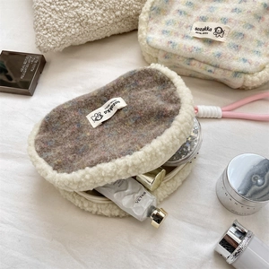 Detail view of plush makeup pouch showing interior capacity with cosmetics and fuzzy texture