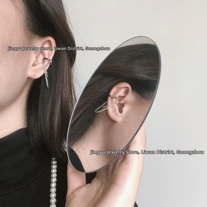 Close-up of a silver non-piercing double chain ear cuff with disc pendant on model
