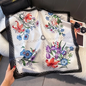 Dettaglio di un foulard quadrato in raso di lusso con stampe floreali e motivi a catena