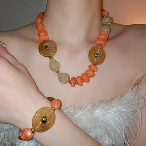 Detail of acrylic irregular beads necklace and bracelet set in orange and amber on model