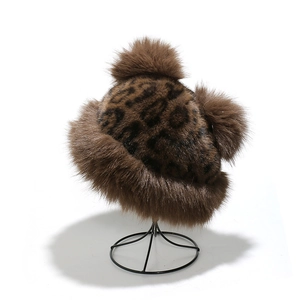Detail of leopard print faux fur winter hat with plush pom-poms on metal display stand