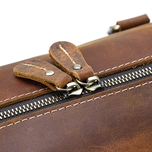 Detail of premium double leather pullers and metal zipper on vintage leather travel bag