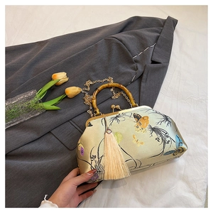 Close-up of vintage embroidery bag with bamboo handle and delicate butterfly patterns