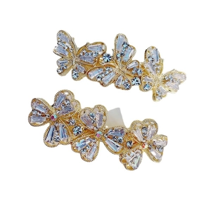 Sparkling gold butterfly and flower hair clips set with rhinestones on white background