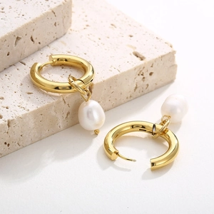 Détail de boucles d'oreilles anneaux dorés avec perles sur une pierre de décoration