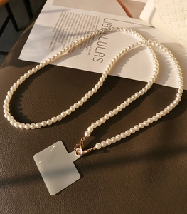 Detailed view of handmade pearl phone strap with golden metal clasp and transparent insert