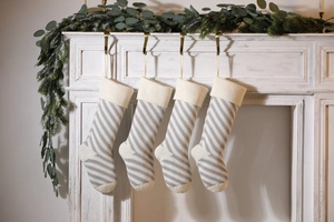 Detailed view of four grey and white striped knitted Christmas stockings on a mantel