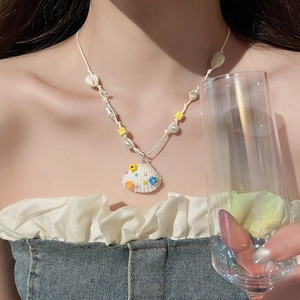 Nahaufnahme der Muschelkette mit bunten Blumen und Perlen auf weißem Webseil