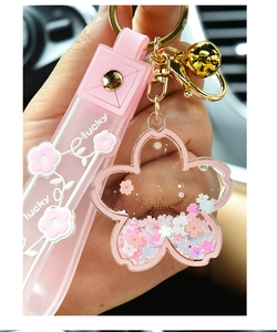 Close-up of pink cherry blossom liquid keychain with floating glitter and lucky strap