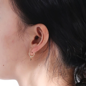 Close-up of golden hoop earrings with evil eye pendant worn by a model for a realistic look