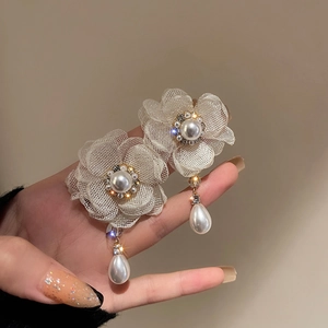 Detailed macro view of beige mesh flower earrings with pearls and crystals