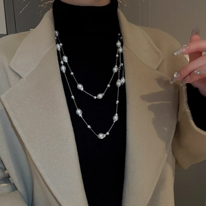 Elegant multi-layered long pearl necklace with silver chain on model in black top